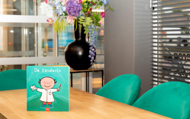 Wachtkamer van TCW met groene stoelen en een kinderboek op tafel